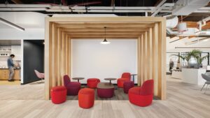 Red Teknion furniture in a wood room with white walls.