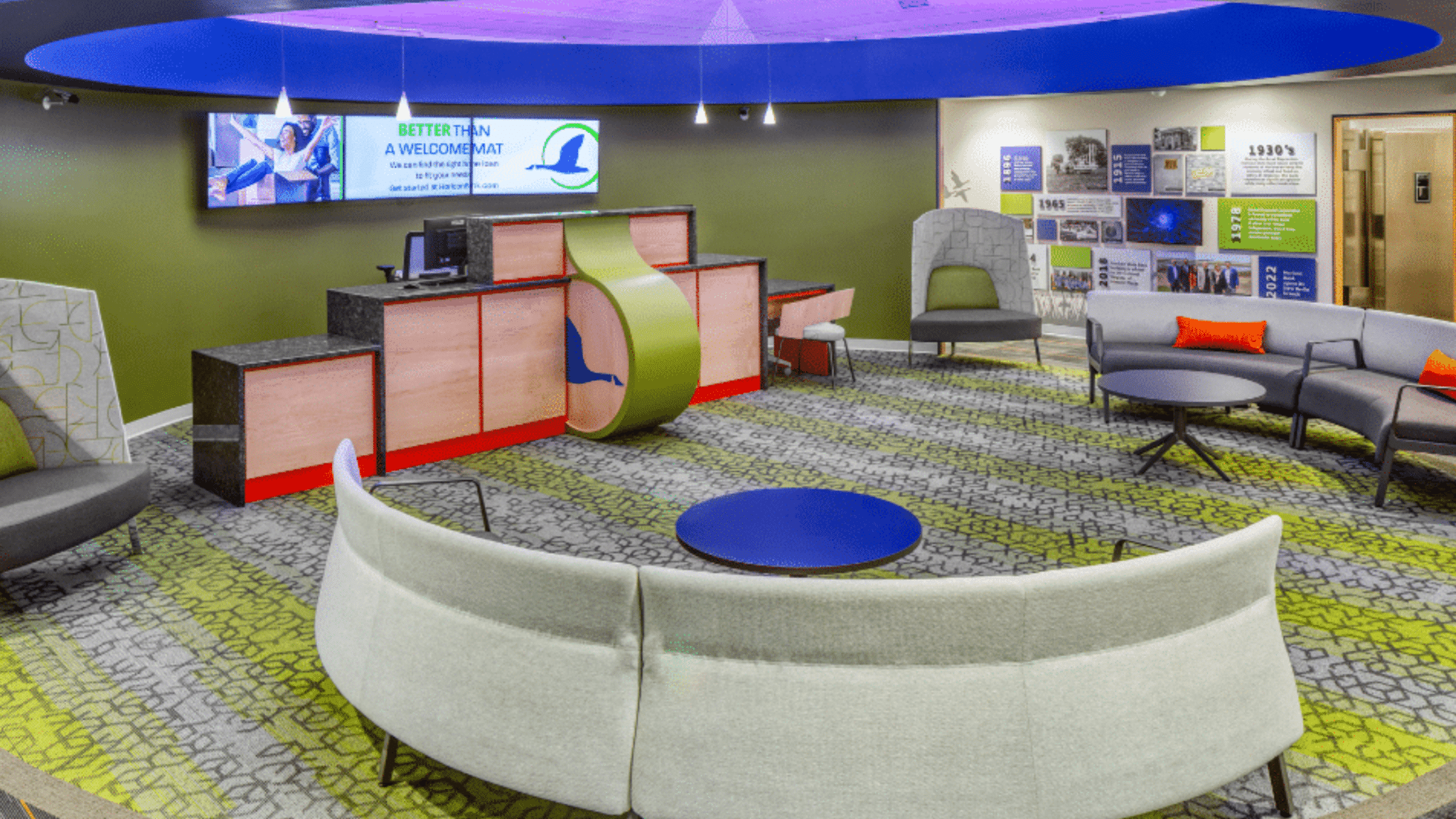A contemporary workplace with green, grey, blue, and orange design elements that showcase a unique reception desk design