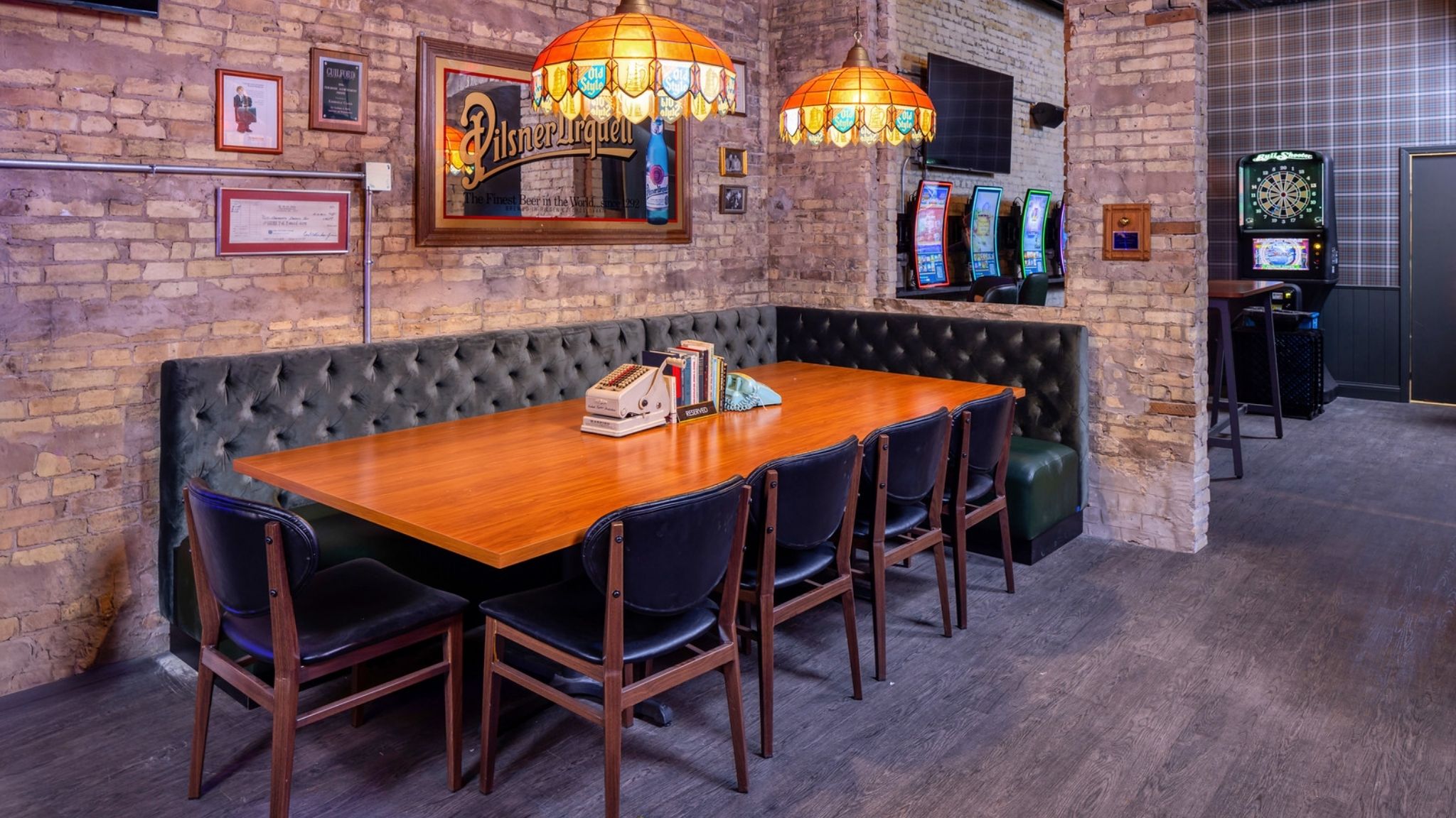 Vintage inspired cocktail bar interior in downtown Milwaukee designed by CJ & Associates featuring tufted booth seating, exposed brick walls, custom furnishings, and warm pendant lighting.